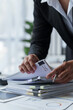 © Phimwilai - Asian businesswoman searches through piles of financial documents to make calculations Marketing analysis Tax administration Statistical accounting report on the desk in the office office.