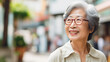 Portrait of an happy elderly asian lady outdoors in street with copy space