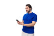 © Ivan Traimak - young caucasian brunette man with a beard in a blue t-shirt texting on a mobile phone