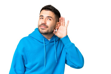 Wall Mural - Young handsome caucasian man over isolated chroma key background listening to something by putting hand on the ear