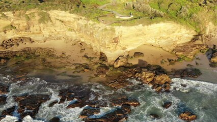 Canvas Print - Pacific coast rocks at sea caves of Caves beach in aerial landscape flying as 4k.
