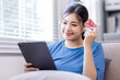 © David - Mobile Shopping. Cheerful Asian Woman Using Smartphone Shopping Online Holding Credit Card Making Payment Sitting At Sofa At Home. Internet Banking Application And E-Commerce