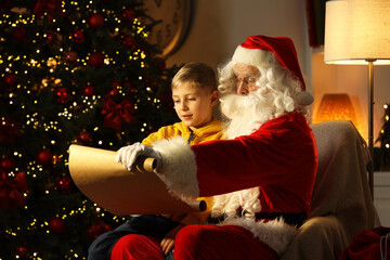 Sticker - Santa Claus with little boy reading letter near Christmas tree in room