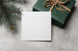 White square paper card mockup with gift box on grey concrete background, blank card mock up with copy space