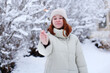 © Olga - Cheerful young woman holding a sparkler in hand in the winter forest. Christmas, New year.
