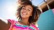 Teen african American girl taking a selfie in the summer. Afro hair girl taking selfie sunset. Happy multiracial student having fun with smartphone photo camera outside- Warm sun Social media 