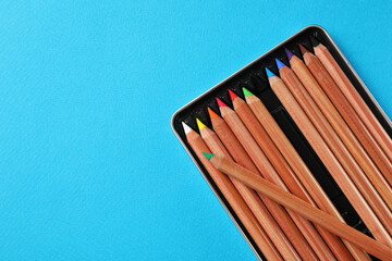 Poster - Box with many colorful pastel pencils on light blue background, top view and space for text. Drawing supplies