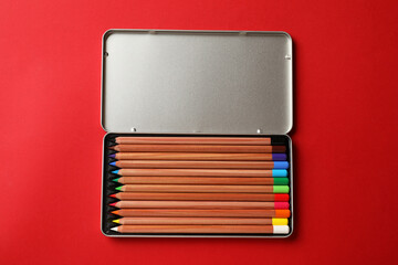 Poster - Box with many colorful pastel pencils on red background, top view. Drawing supplies