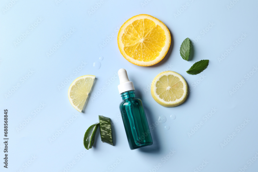 Bottle of cosmetic serum, sliced citrus fruits and aloe vera on light ...