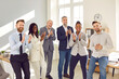 © Studio Romantic - Happy diverse business team clapping hands together. Group of joyful multiethnic people standing in office, applauding and smiling. Work recognition, success, appreciation concept
