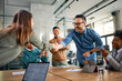 © Drazen - Happy businessman handshaking with female colleague during meeting in office while others are applauding.