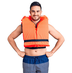 Wall Mural - Young handsome man wearing lifejacket happy face smiling with crossed arms looking at the camera. positive person.