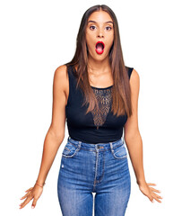 Wall Mural - Young hispanic woman wearing casual clothes afraid and shocked with surprise and amazed expression, fear and excited face.