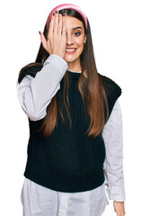Wall Mural - Young beautiful woman wearing casual white shirt covering one eye with hand, confident smile on face and surprise emotion.