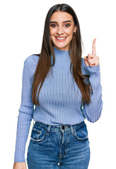 Wall Mural - Young beautiful woman wearing casual winter sweater pointing finger up with successful idea. exited and happy. number one.