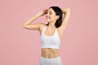 © Prostock-studio - Slim young lady athlete in sportswear enjoy workout, stretching hands on pink studio background