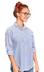 Poster - Young redhead woman wearing casual clothes and glasses looking away to side with smile on face, natural expression. laughing confident.