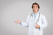Smiling male doctor in lab coat gesturing with hand on grey background