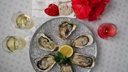 Wall Mural - Fresh oysters on ice rotating, Valentines Day, glasses of champagne. Top view