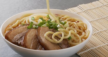 Wall Mural - Asian ramen noodles soup with egg, pork and onion. Close-up footage. Chopsticks take noodles.