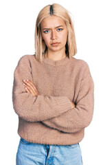 Poster - Beautiful young blonde woman wearing brown sweater skeptic and nervous, disapproving expression on face with crossed arms. negative person.