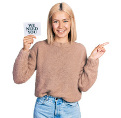 Poster - Beautiful young blonde woman holding we need a change banner smiling happy pointing with hand and finger to the side