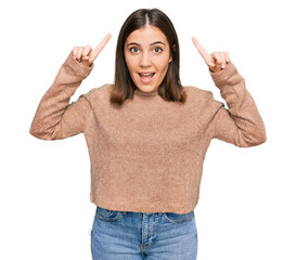 Sticker - Young beautiful woman wearing casual clothes smiling amazed and surprised and pointing up with fingers and raised arms.