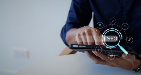 Poster - SEO concept. A businessman's hand holds the iPad and presses the button with an SEO icon for optimizing your website to rank in search engines or SEO, Monitoring and analyzing data.	