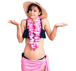 Poster - Beautiful young woman with short hair wearing bikini and hawaiian lei clueless and confused expression with arms and hands raised. doubt concept.