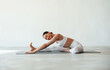 © standret - Stretching the legs. Fitness woman is indoors in white clothes