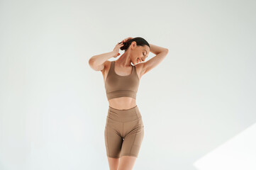 Woman in fitness clothes is standing against white background