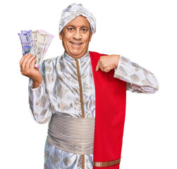 Canvas Print - Senior hispanic man wearing sherwani costume holding indian rupee banknotes pointing finger to one self smiling happy and proud