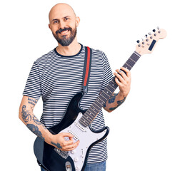 Young handsome man playing electric guitar looking positive and happy standing and smiling with a confident smile showing teeth