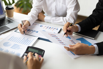 Business people and colleagues brainstorm together analyzing charts, financial reports and market growth graphs to plan new business investment strategies. Meeting to discuss statistical analysis.