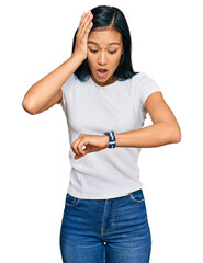 Sticker - Beautiful hispanic woman wearing casual white tshirt looking at the watch time worried, afraid of getting late