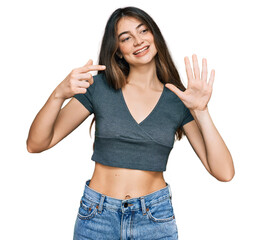 Wall Mural - Young beautiful teen girl wearing casual crop top t shirt showing and pointing up with fingers number seven while smiling confident and happy.