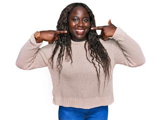 Poster - Young african woman wearing wool winter sweater smiling cheerful showing and pointing with fingers teeth and mouth. dental health concept.