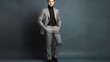 Handsome fashion man in turtleneck, gray coat, plaid trousers and leather loafer boots stands isolated on wall background.