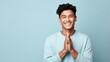 close-up of a lovely Against an isolated light blue studio background, a handsome and smiling young Southeast Asian man impressively claps his hands.