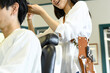 男性客の髪を切る美容師のアジア人女性