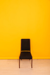 Wall Mural - One black chair against a yellow wall