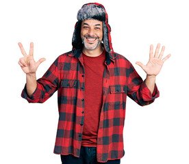 Sticker - Middle age hispanic man with grey hair wearing fluffy earmuff hat showing and pointing up with fingers number eight while smiling confident and happy.