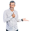 © Krakenimages.com - Middle age hispanic with grey hair wearing casual white shirt showing palm hand and doing ok gesture with thumbs up, smiling happy and cheerful