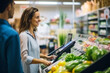 © Hunman - Profile view of a young woman paying with a credit card to a store clerk in a supermarket.