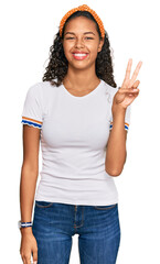 Sticker - Young african american girl wearing casual clothes showing and pointing up with fingers number two while smiling confident and happy.