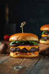 Two delicious homemade burgers of beef, cheese and mushrooms on an wooden table. Fat unhealthy food