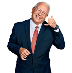 Canvas Print - Senior man with grey hair wearing business suit and glasses smiling doing phone gesture with hand and fingers like talking on the telephone. communicating concepts.