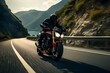 Man rides a motorcycle in a curved asphalt road with rural and mountain background