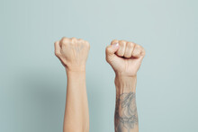 Two Fists Raised Against A Blue Background. Concept Of Strength And Unity.