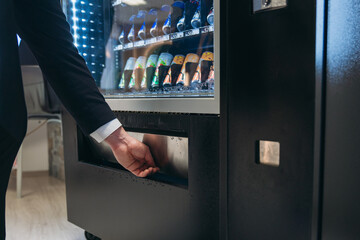 Close up hand of man pushing button on vending machine for choosing a snack or drink. Small business and consumption concept.